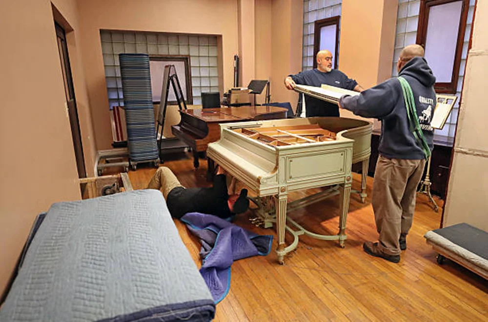 two people disassembling a piano